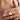 The woman is wearing a open Gold sun necklace and is holding the pendant on her fingers.