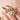 A woman has a rose gold epen necklace and an engravable pendant in her fingers.