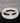 On a white round table, there are black lava and white stone bracelets on top of each other.