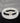 On a white round table, there are black lava and white stone bracelets on top of each other.