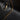There is a gold colored curb chain on a black background.