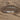 There is a gray metal plate on the sand. There is a bracelet on this plate.